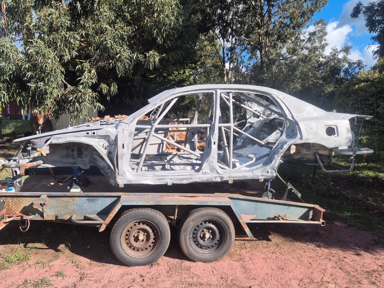 Rally car shell with full roll cage on a trailer, blasted clean